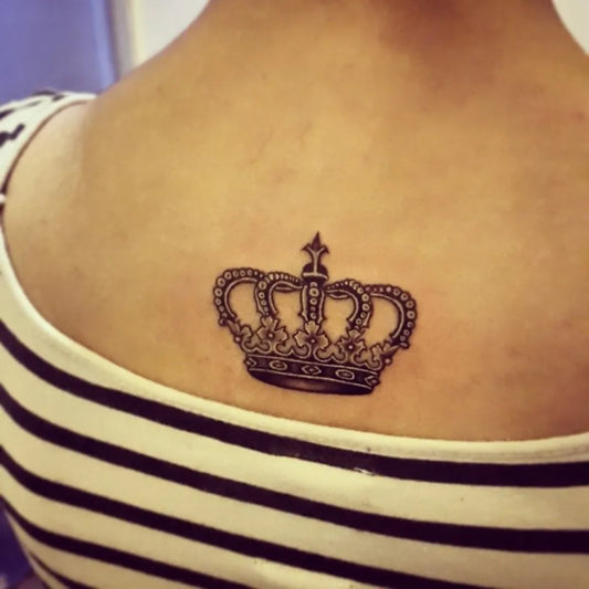 Small Black and Grey Crown Tattoo on Women Back by @coilbugparmeet