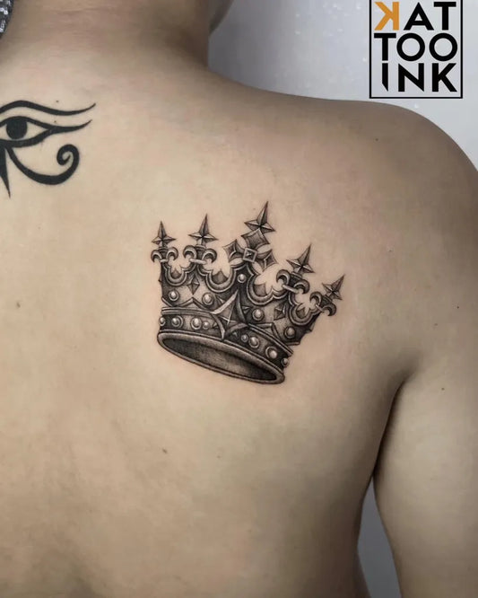 Small Black and Grey Crown and Eye of Horus Tattoo on Women Shoulder by @kat.tattooink
