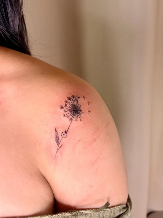 Small Black and Grey Dandelion Tattoo on Women Shoulder by @theevieedit_pmu