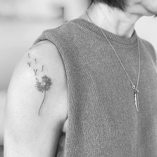Small Black and Grey Dandelion Tattoo on Women Shoulder by @tiny.tatu.uk