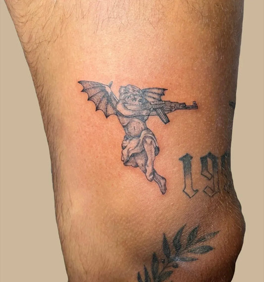 Small Black and Grey Demon Angel with Rifle Tattoo on Men Thigh by @aida.dzi.tattoo