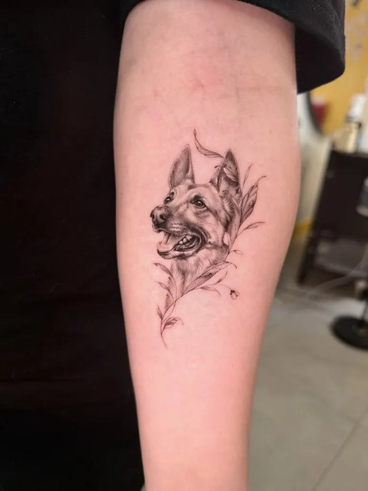 Small Black and Grey Dog with Flowers Tattoo on Women Arm by @baronarttattoo