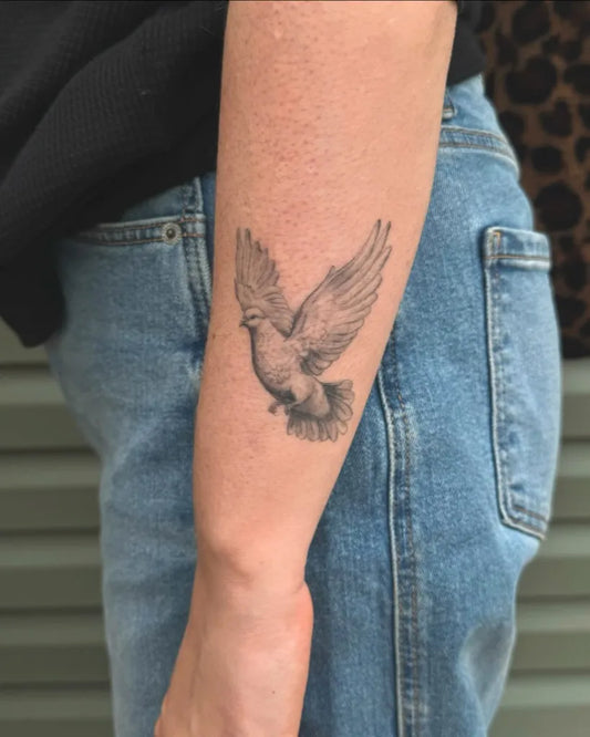Small Black and Grey Dove Tattoo on Women Arm by @melaniejill.tattoo