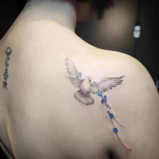 Small Black and Grey Dove with Flowers Tattoo on Women Shoulder by @enigmcd