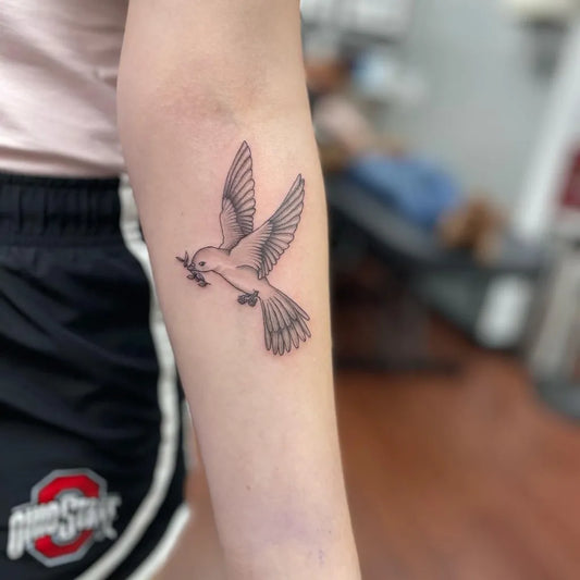 Small Black and Grey Dove with Olive Branch Tattoo on Women Arm by @tattoos_by_amanda_cutcher