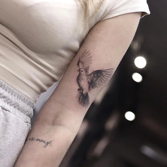 Small Black and Grey Dove with Script Tattoo on Women Arm by @scorpio.aalst
