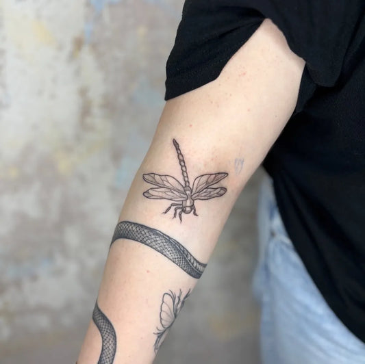 Small Black and Grey Dragonfly Snake Flower on Women Arm Tattoo by @moonshinegarden.tattoo