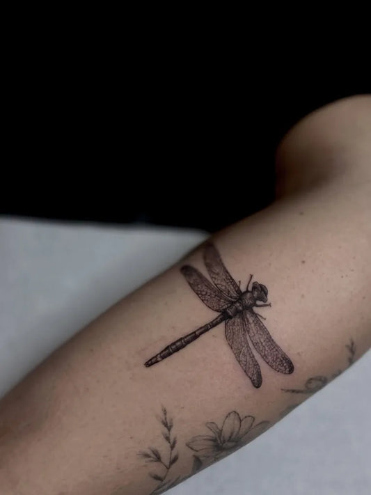 Small Black and Grey Dragonfly and Flowers on Women Arm Tattoo by @foundingmother.tattoos