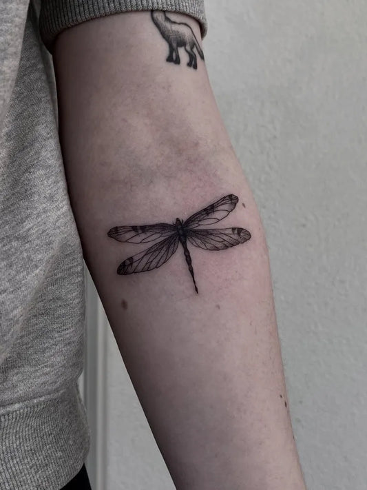 Small Black and Grey Dragonfly on Women Arm Tattoo by @goblinked
