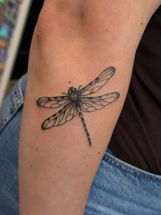 Small Black and Grey Dragonfly on Women Arm Tattoo by @ink_ya.later