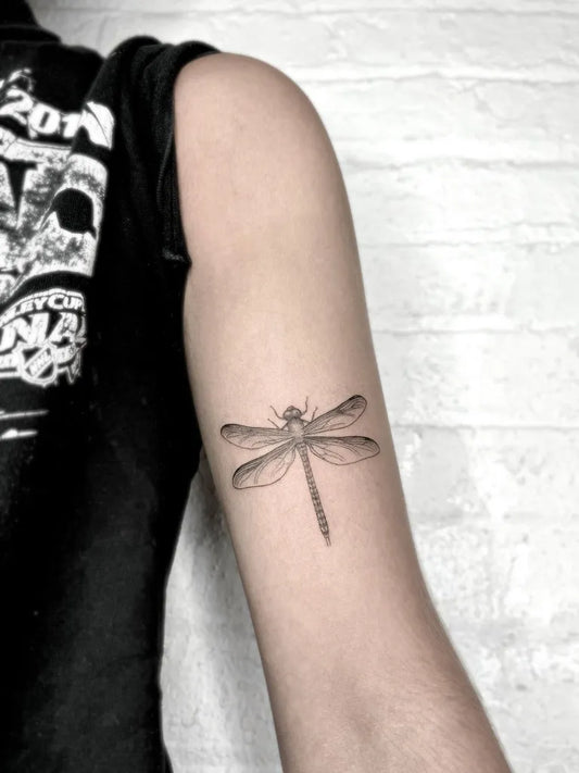Small Black and Grey Dragonfly on Women Arm Tattoo by @melanie.benyahya