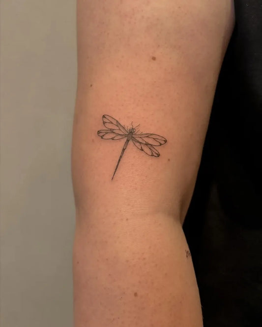 Small Black and Grey Dragonfly on Women Arm Tattoo by @pauline.tattoo