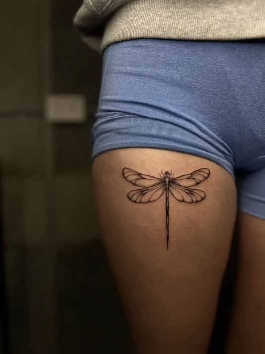 Small Black and Grey Dragonfly on Women Thigh Tattoo by @trinny.h.art