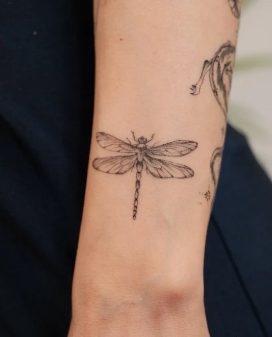Small Black and Grey Dragonfly on Women Wrist Tattoo by @lovemore.tattoo