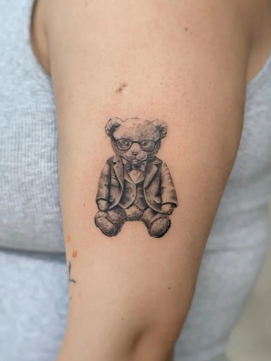 Small Black and Grey Dressed Bear with Glasses on Women Arm Tattoo by @b36tattoo