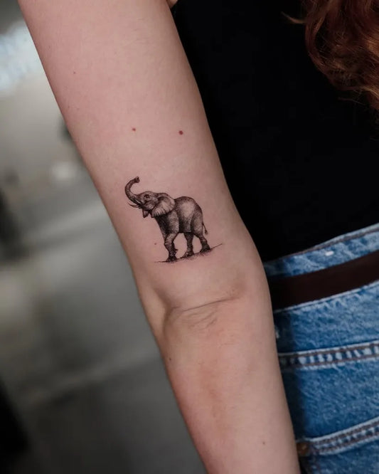 Small Black and Grey Elephant Tattoo on Women Arm by @piranhatattoostudios