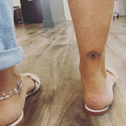 Small Black and Grey Evil Eye on Women Ankle Tattoo by @basetoface_finelinetats