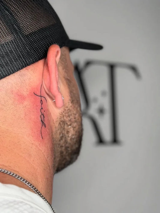 Small Black and Grey Faith Word Tattoo on Men Behind the Ear by @anatzz.tattoo