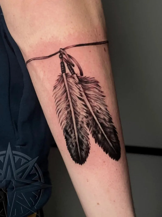 Small Black and Grey Feather Tattoo on Men Arm by @babilontattookilkenny