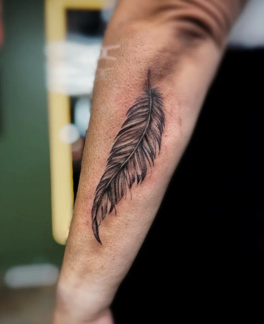 Small Black and Grey Feather Tattoo on Women Arm by @cleotattratattoos