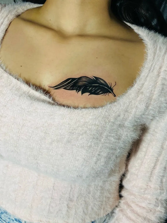 Small Black and Grey Feather Tattoo on Women Chest by @colours_tattoo_piercing_studio