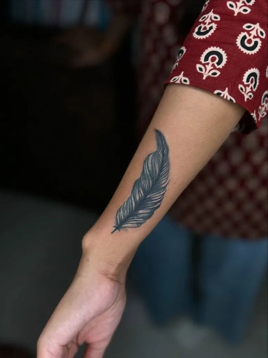 Small Black and Grey Feather Tattoo on Women Forearm by @kabirainktattooandpiercing
