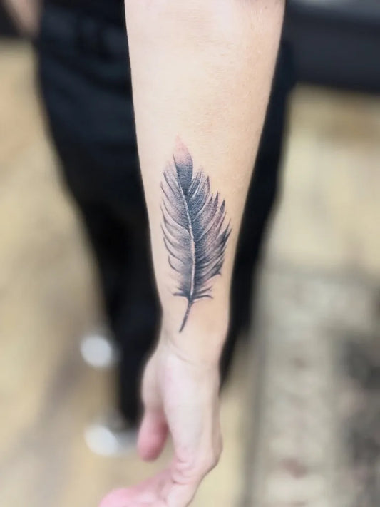 Small Black and Grey Feather Tattoo on Women Forearm by @solidinktattoostudio