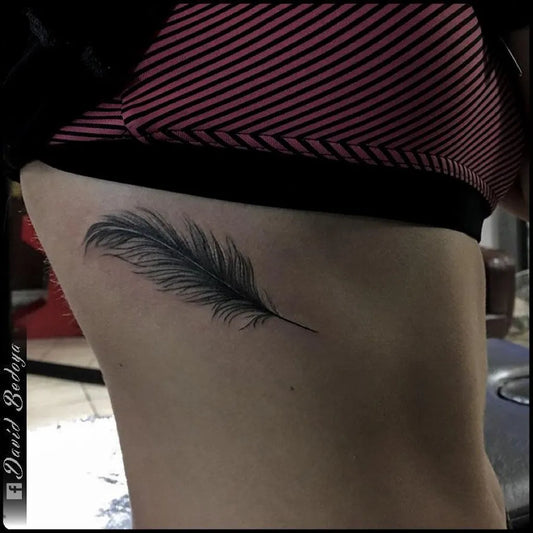 Small Black and Grey Feather Tattoo on Women Rib by @davidbedoyatattoo