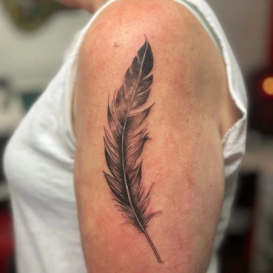 Small Black and Grey Feather Tattoo on Women Upper Arm by @hustletattoo_