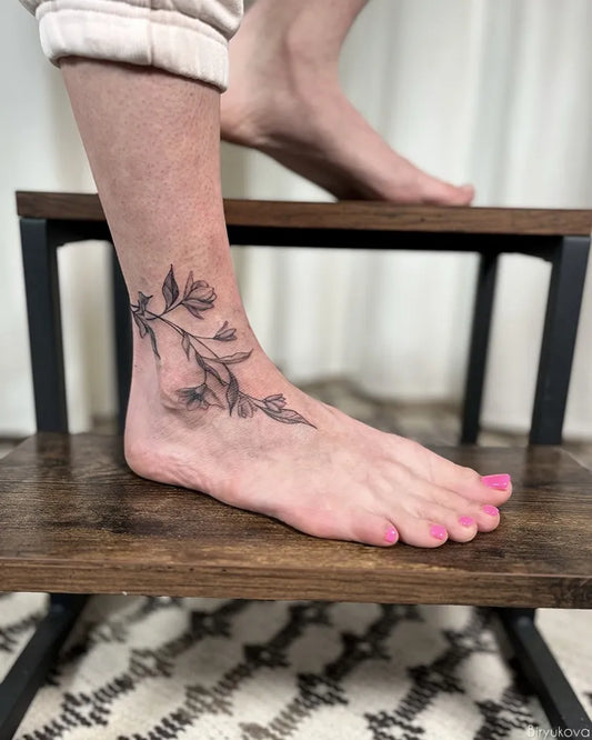 Small Black and Grey Floral Vine Tattoo on Women Ankle by @biryukova.t