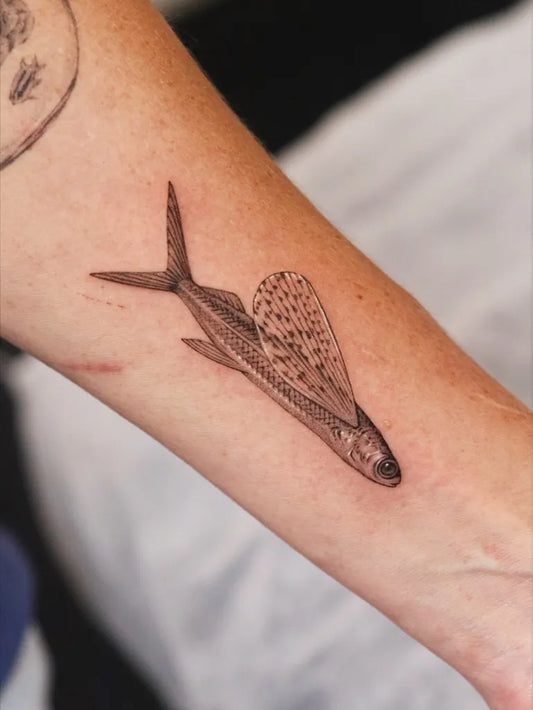 Small Black and Grey Flying Fish Tattoo on Women Arm by @yonder.tattoo