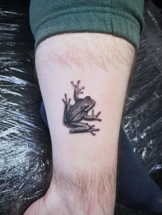 Small Black and Grey Frog Tattoo on Men Forearm by @trinity.tatt