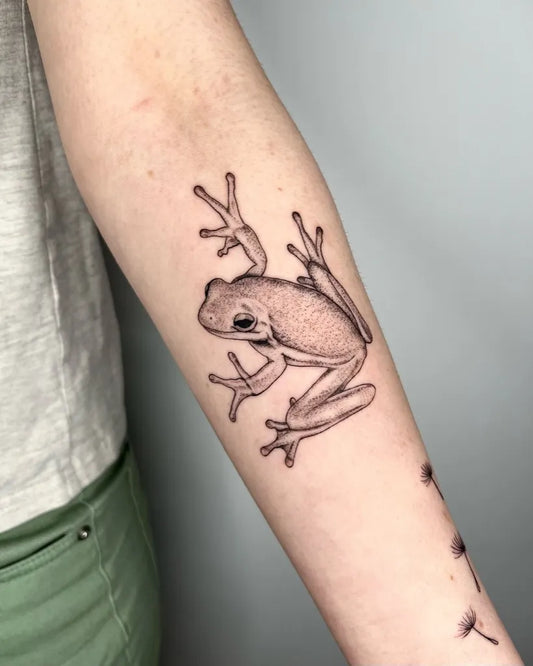 Small Black and Grey Frog Tattoo on Women Arm by @iriswoodtattoo