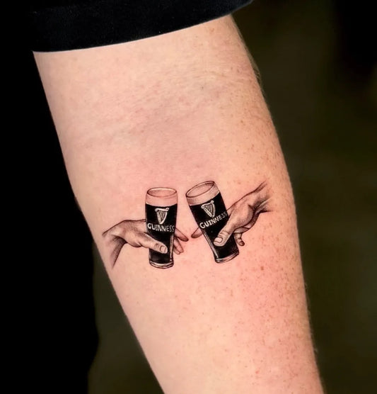 Small Black and Grey Guinness Glasses Hands Tattoo on Women Arm by @ruth.tatts