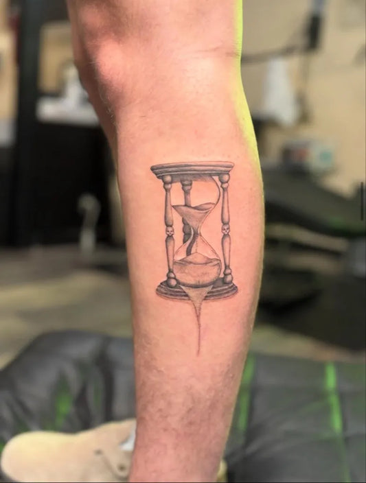 Small Black and Grey Hourglass Tattoo on Men Leg by @burnedheartstattoos