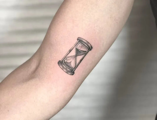 Small Black and Grey Hourglass Tattoo on Women Upper Arm by @inkparktattookop