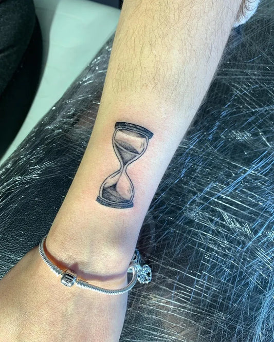 Small Black and Grey Hourglass Tattoo on Women Wrist by @stoictattoos