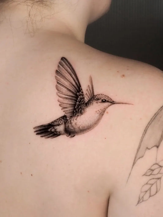 Small Black and Grey Hummingbird Tattoo on Women Shoulder by @bluerain.tattoo