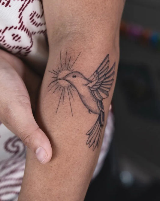 Small Black and Grey Hummingbird with Sun on Women Arm Tattoo by @inkykimi