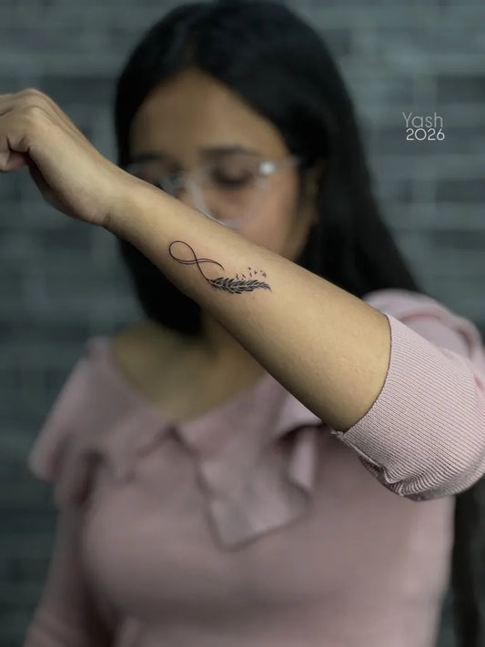Small Black and Grey Infinity Feather Tattoo on Women Wrist by @houseof__shades