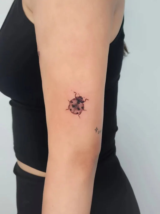 Small Black and Grey Ladybug Tattoo on Women Arm by @dalette_tattoo