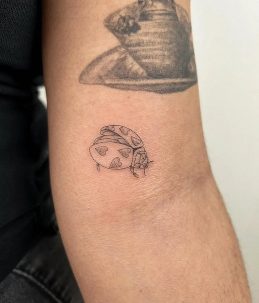 Small Black and Grey Ladybug Tattoo on Women Arm by @hellymarch_tattoo
