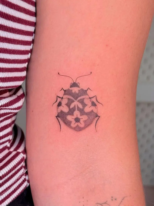 Small Black and Grey Ladybug Tattoo on Women Arm by @raissa.ink
