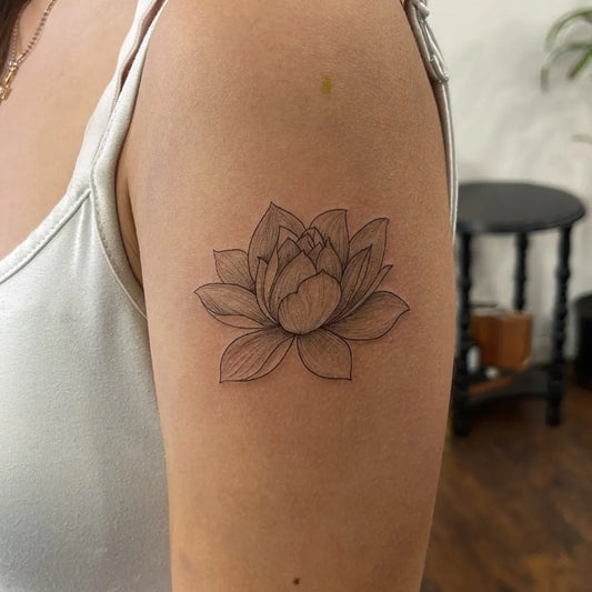 Small Black and Grey Lotus Flower on Women Upper Arm Tattoo by @inkfusion_tattoo_studio