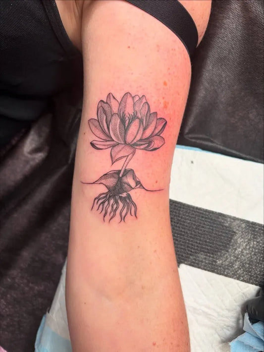 Small Black and Grey Lotus Flower with Roots on Women Arm Tattoo by @y2kass.tattoos
