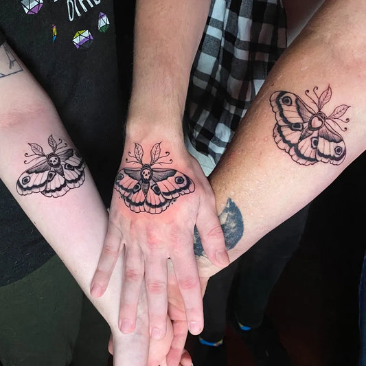 Small Black and Grey Luna Moth Family Tattoo on Women Hand by @fifthfingerstudio