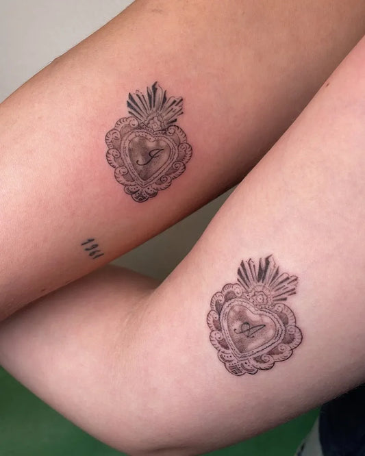 Small Black and Grey Matching Sacred Heart with Crown Tattoo on Women Arm by @gentlescratches
