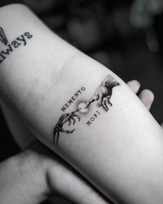 Small Black and Grey Memento Mori Hands Tattoo on Women Arm by @goodomengallery