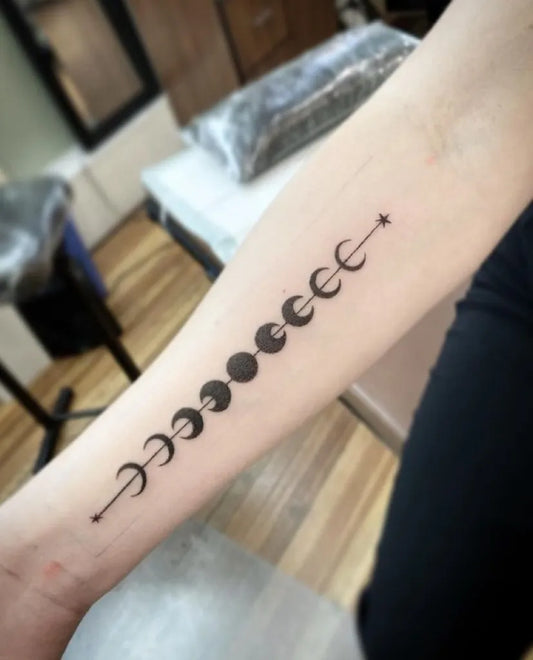 Small Black and Grey Moon Phases Tattoo on Women Arm by @alchemytattoocollective