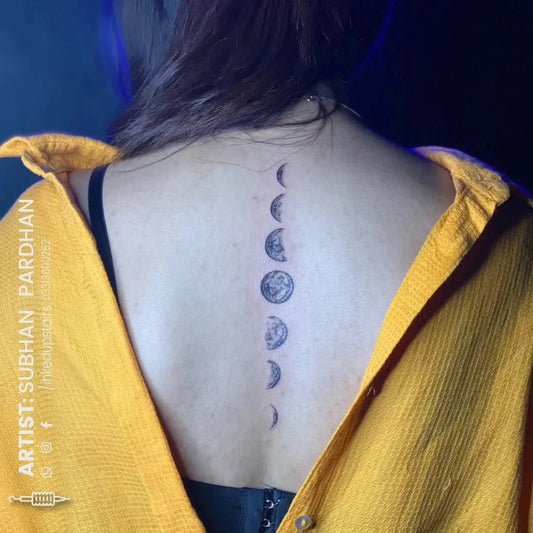 Small Black and Grey Moon Phases Tattoo on Women Back by @inkedupstairs.tattoostudio
